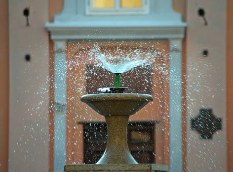 droplets dispersing from a fountain and buildings in background