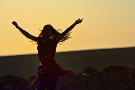 Teen girl jump against beautiful sunset on field