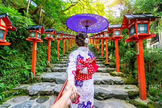 woman wearing japanese traditional kimono holding man's hand and leading him to Kifune shrine, Kyoto in Japan.
