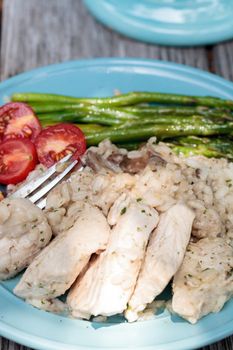 Sauteed pork and asparagus with mushroom risotto meal on a rustic dinner plate