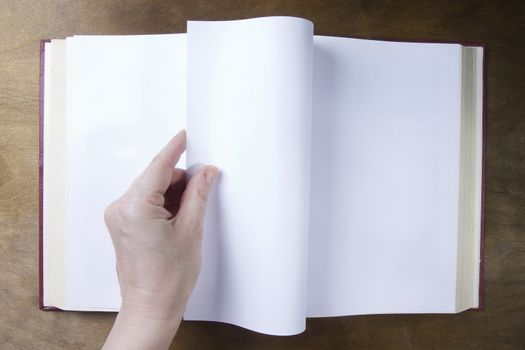 Hand turns the blank sheet of books on a wooden table