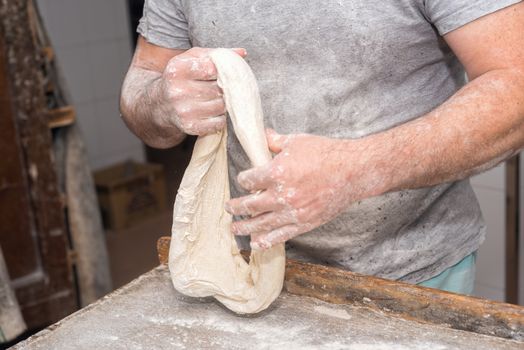 Baker hands kneading bread dough 