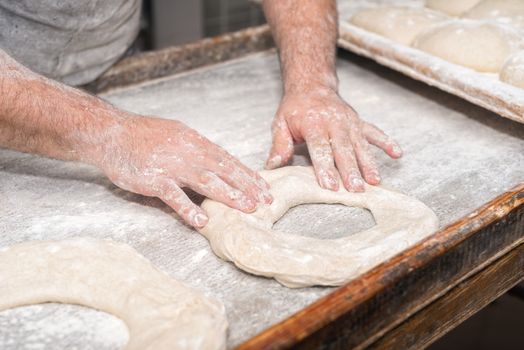 Baker hands kneading bread dough 
