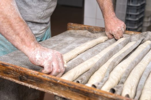 Baker hands preparing uncooked bread loafs ready to bake