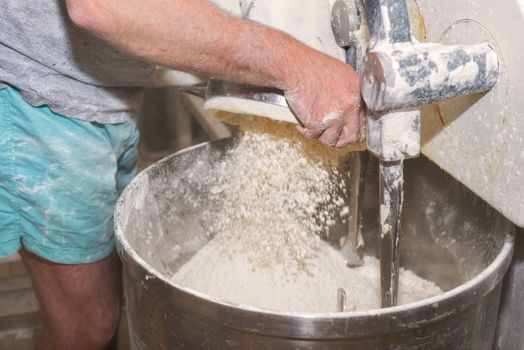 Loading flour into an industrial bakery dough mixer.