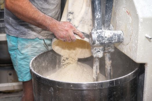 Loading flour into an industrial bakery dough mixer.