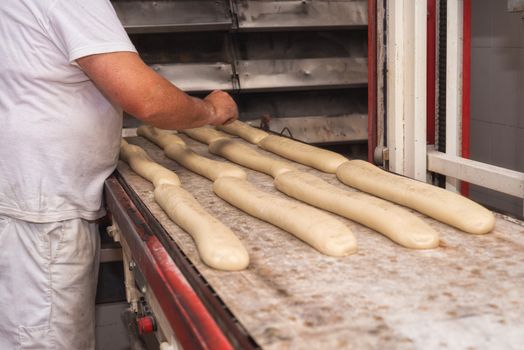 Baker preparing uncooked bread dough loaves ready to bake