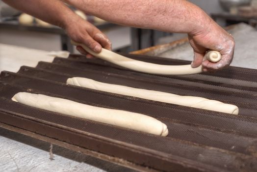 Baker preparing uncooked bread dough loaves ready to bake