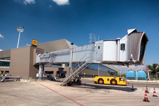 Aero gangway bridge, boarding bridge on airport with yellow tow tractor beneath