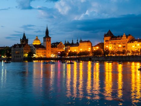 Historical buildings of Smetana Embankment reflected in the water of Vltava River on summer evening. Prague, Czech Republic.