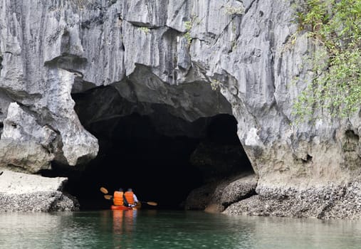 Cayakers entering a sea cave in Ha Long bay