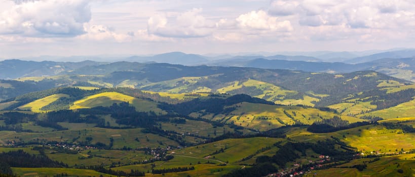 summer landscape. village on the hillside. forest on the mountain light fall on clearing on mountains