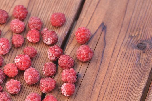 Covered with frothy raspberries is on the left side of a wooden board, a photo from above