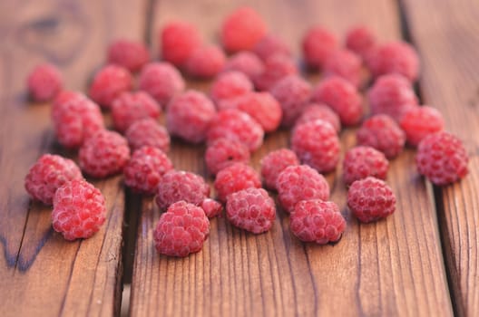 On a wooden background, raspberries spread across the plane, photos on the side