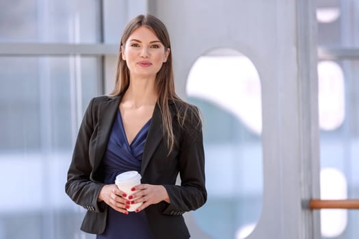 Business woman having break with takeaway coffee in modern place