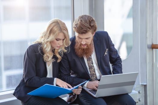 Business people having a break, sitting with laptop and documents and talking