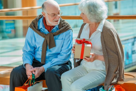 Senior couple in shopping mall with gifts