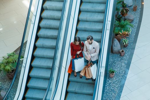 Happy beautiful young couple with shopping bags in mall