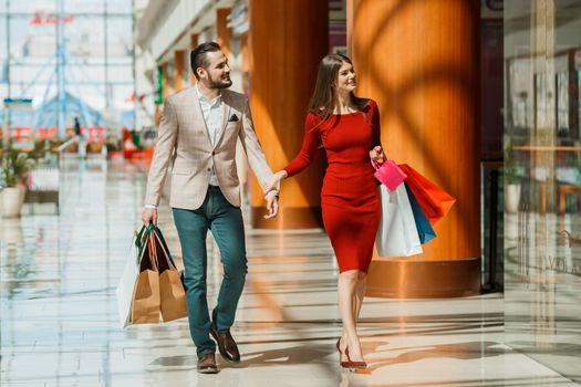 Happy beautiful young couple with shopping bags in mall