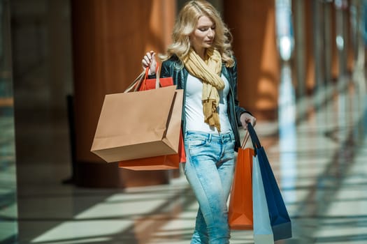 Sale and people - smiling woman with colorful shopping bags over supermarket background