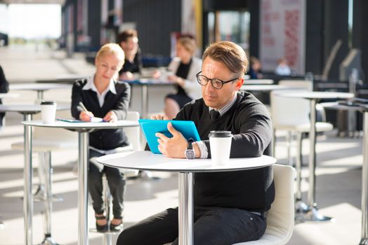 Lot of business people sitting in cafe of modern office building