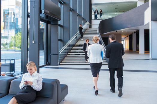 Modern business people walking in glass hall of office building