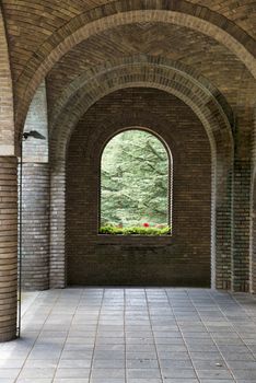 corridor with bow from old stones with green plants and red flowers at the end of this background wallpaper