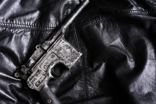 Old military pistol on black leather background