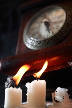 Vintage still life with lighting candles near old clock