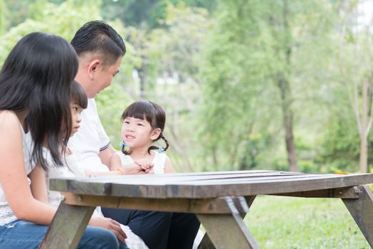 Asian family enjoying nature at outdoor park. Empty space on wooden table.