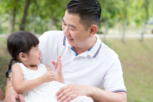 Happy father and daughter bonding at green park. Asian family outdoors activity.