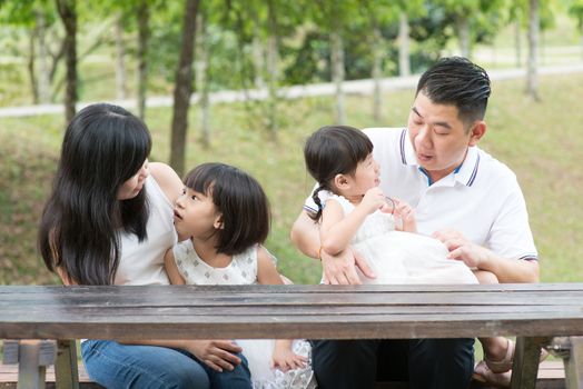 Asian family. Parents and children bonding at outdoor park. Empty space on wooden table.