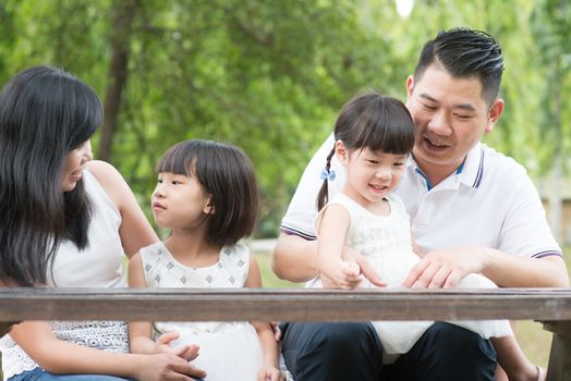Asian family. Parents and children having fun at outdoor park. Empty space on wooden table.
