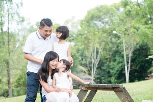 Asian family portrait. Parents and children having fun at outdoor park. Empty space on wooden table.