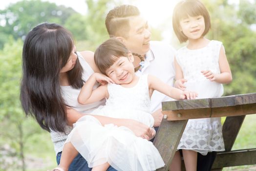 Asian family portrait. Parents and children at outdoor park. Blank space on wooden table.