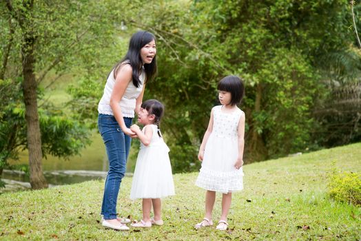 Mother comforting crying daughter at outdoor park. Asian family outdoors portrait.