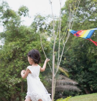 Asian family outdoors activity. Little girl running and flying kite at park. 