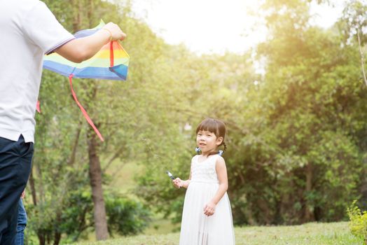 Asian family outdoors activity. Father and daughter flying kite at garden park. 