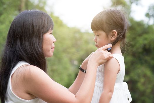 Asian family outdoors portrait. Mother and daughter having fun at green park. 