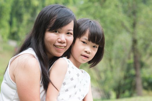 Asian family outdoors portrait. Mother and daughter bonding at garden park. 