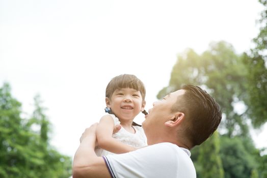 Asian family outdoors portrait. Father and daughter playing at green park. 