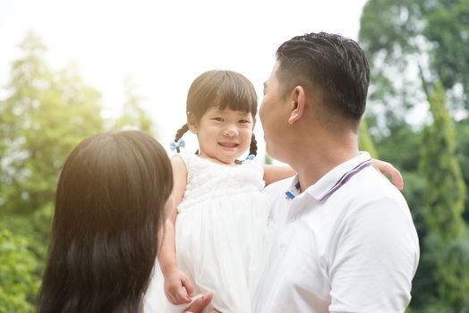 Happy parents and child at green park. Asian family outdoors activity.