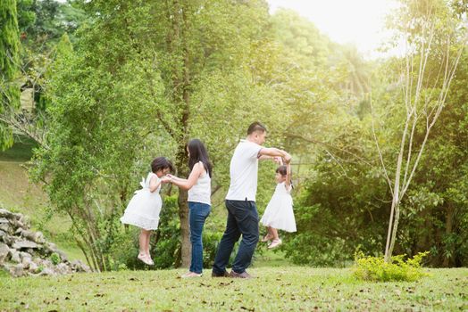 Asian family outdoors. Parents and children playing at garden park. 