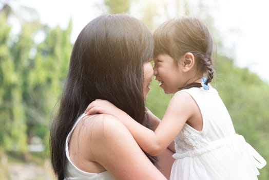 Asian family outdoors portrait. Mother and daughter having quality time at garden park. 