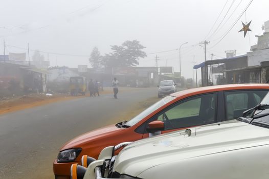 Araku Valley - October, 2017: Red taxi cab parked on empty road. Foggy street scene in winter and rainy weather. Travel vacation holiday concept.