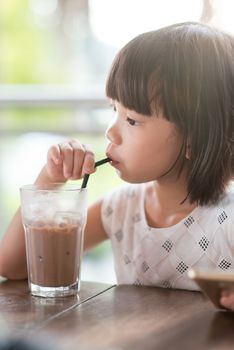 Asian girl drinking iced chocolate at cafe. Natural light outdoor lifestyle.