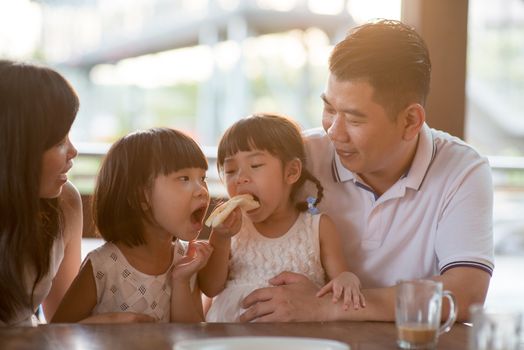 Children eating and sharing butter toast at cafe. Asian family outdoor lifestyle with natural light.