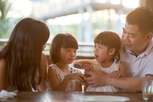 Happy children eating and sharing butter toast at cafeteria. Asian family outdoor lifestyle with natural light.