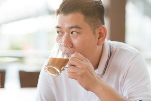 Asian mature man drinking milk tea at cafe. Outdoor lifestyle with natural light.