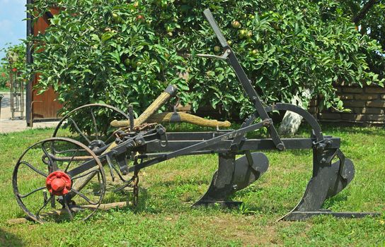 Old restored vintage plow sitting on grass in yard